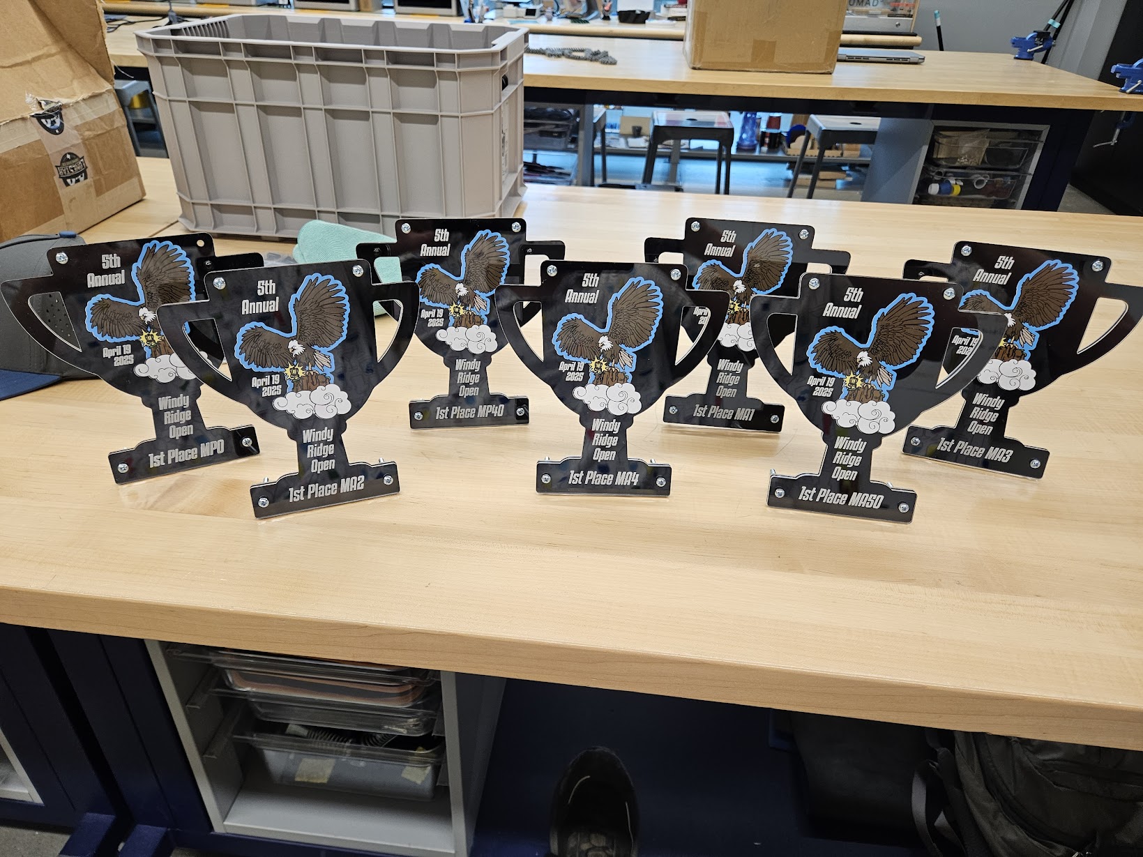A row of black acrylic cup trophies for the 5th annual Windy Ridge Open